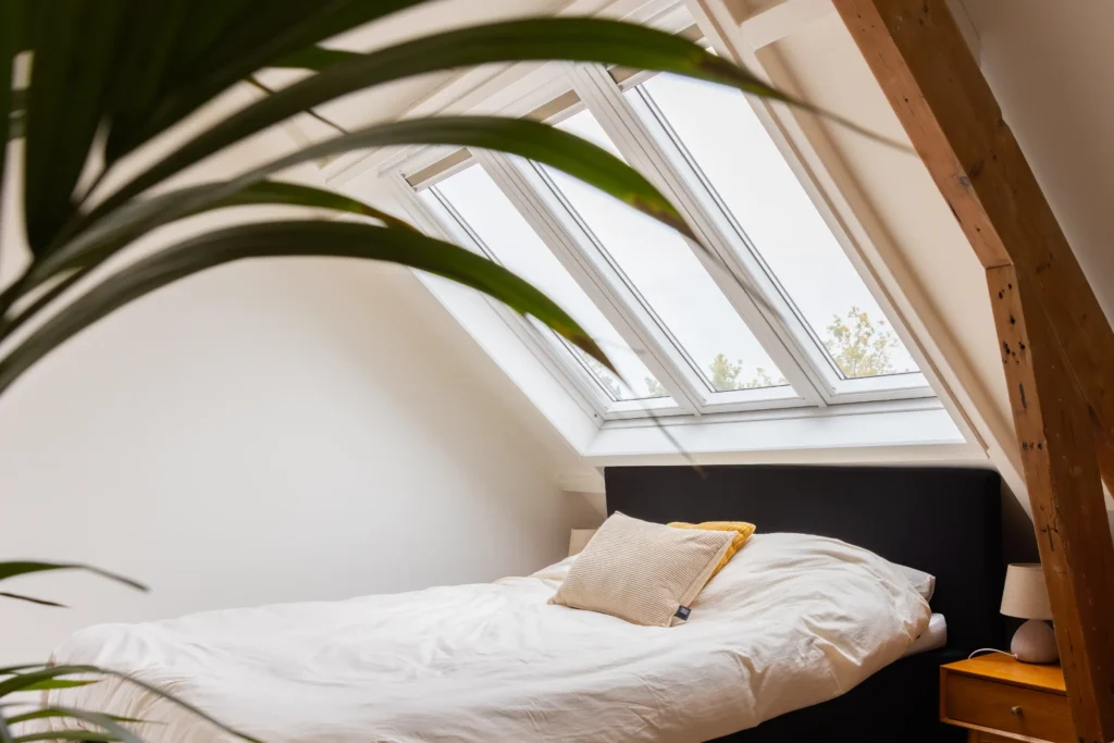Verbouwde zolder met een bed en groot dakraam